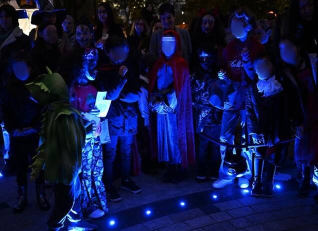 Photo d'enfants déguisés autour d'une fontaine illuminée