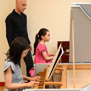 Photo d'un cours de claviers avec le professeurs et deux élèves