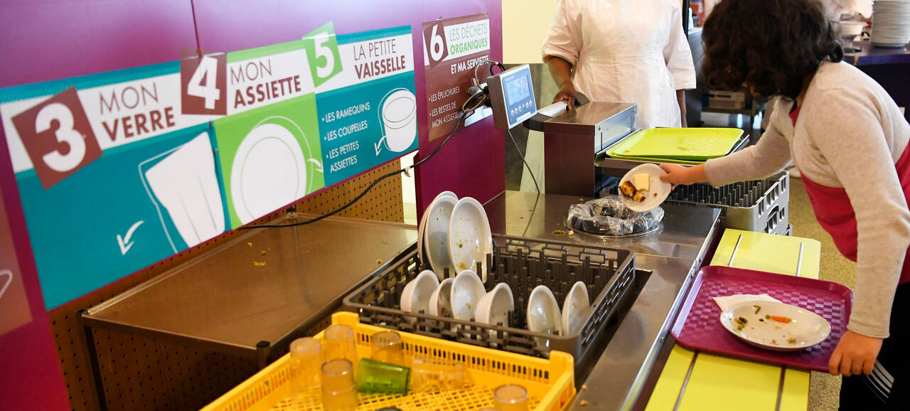 Photo d'une table faisant de la sensibilisation sur les différentes manières de trier ses déchets. On peut voir une enfant trié ses déchets alimentaires dedans