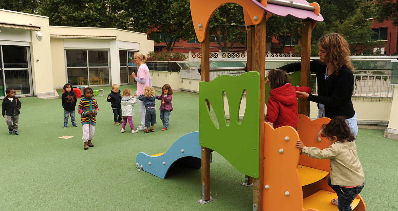 Photo d'enfants se dirigeant vers un toboggan dans une aire de jeux dans une crèche verte